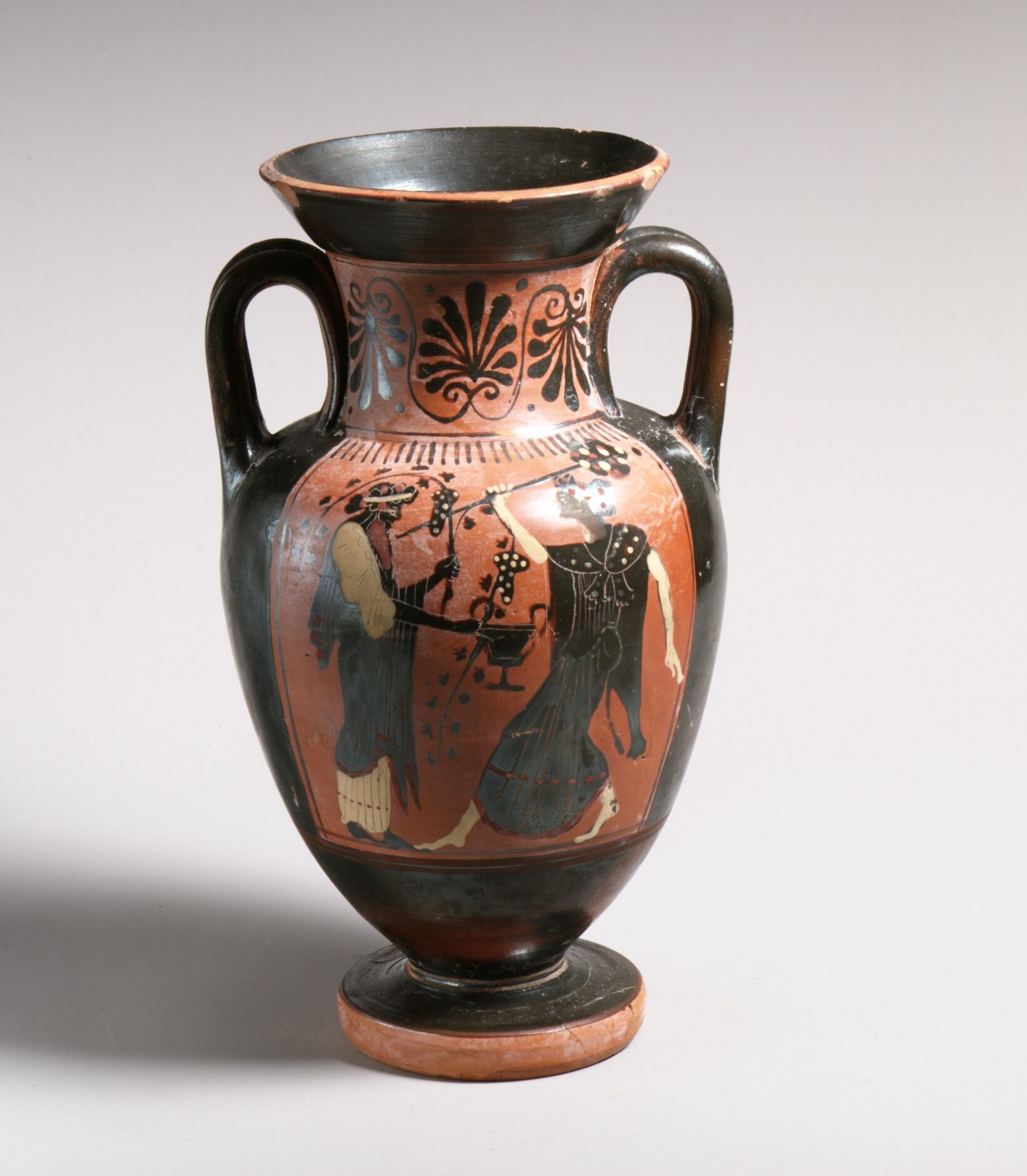 Vase grec à figures noires : un homme barbu couronné de lierre face à une femme en mouvement.