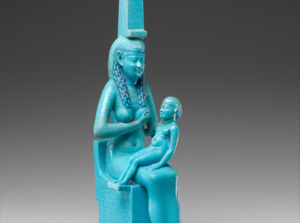Statuette de faïence : une femme assise, coiffée d'un trône hiéroglyphique, allaite un enfant nu assis sur ses genoux.