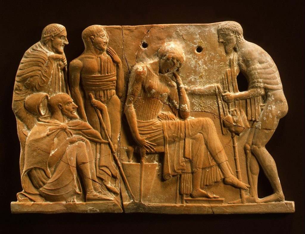 Plaque en terre cuite en relief : un homme en habit de mendiant s’approche d’une femme assise, tête baissée, devant trois personnages.