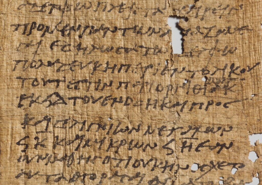 Petit fragment de papyrus brun clair couvert de lignes d'écriture grecque cursive.