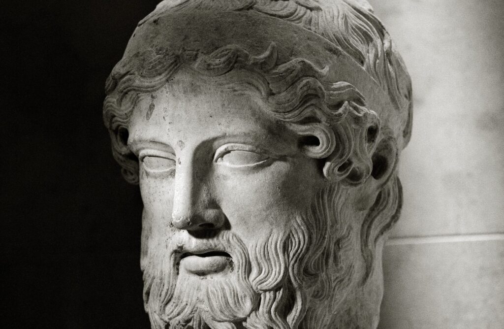Tête sculptée en marbre d'un homme barbu aux cheveux ceints d'un bandeau, le regard porté droit devant.