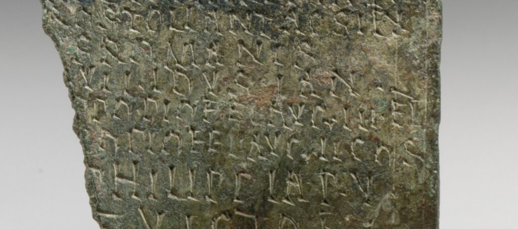 Fragment de plaque de bronze gravée d'un texte latin en petits caractères réguliers.