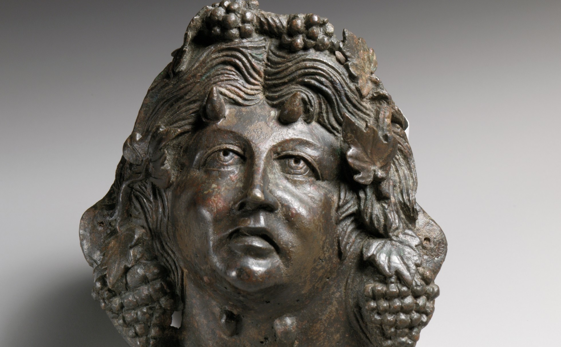 Applique en bronze figurant un visage barbu aux traits marqués, couronné de grappes de raisin et de feuillage.