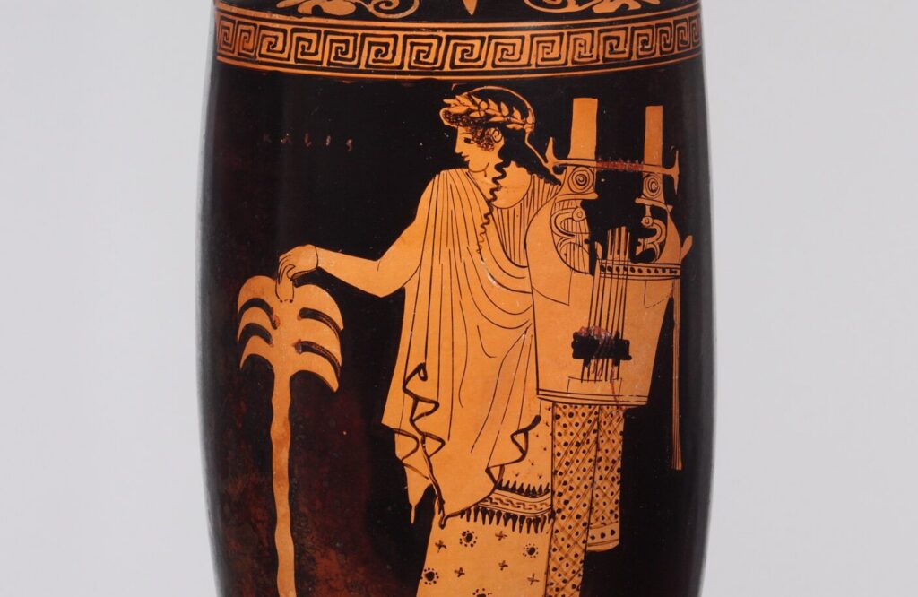 Vase grec à figures rouges : un homme drapé, les cheveux longs, tient une cithare devant un palmier.
