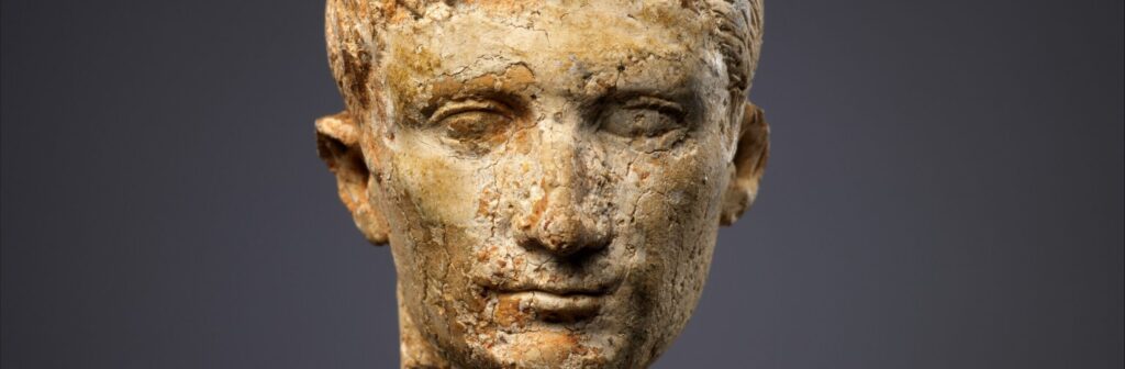 Petite tête sculptée en ivoire, représentant un homme au visage jeune et aux cheveux courts.