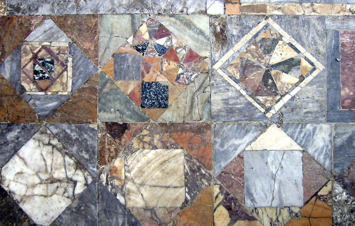 Sol en marqueterie de marbres de couleurs formant un motif géométrique.