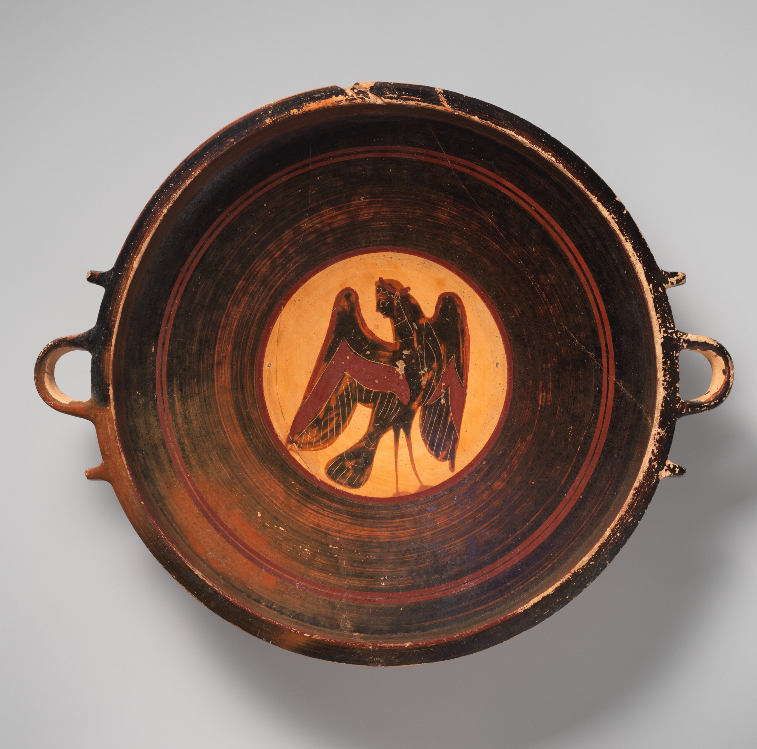 Coupe grecque en terre cuite, ornée au fond d'une figure noire à tête de femme et corps d'oiseau.