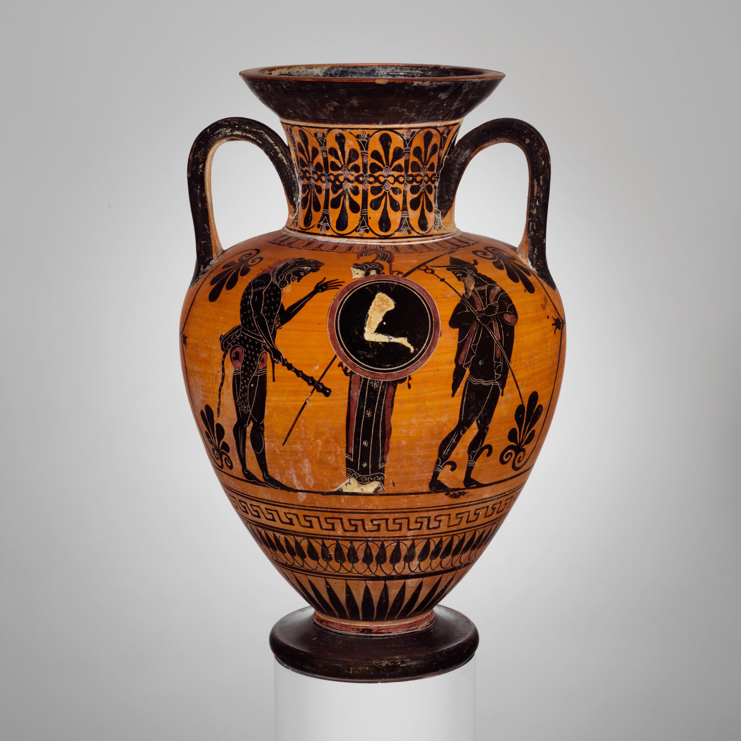Vase grec à figures noires : trois figures debout, un homme vêtu d'une peau de fauve, une divinité casquée au bouclier rond, et un homme coiffé d'un chapeau à larges bords tenant un bâton.