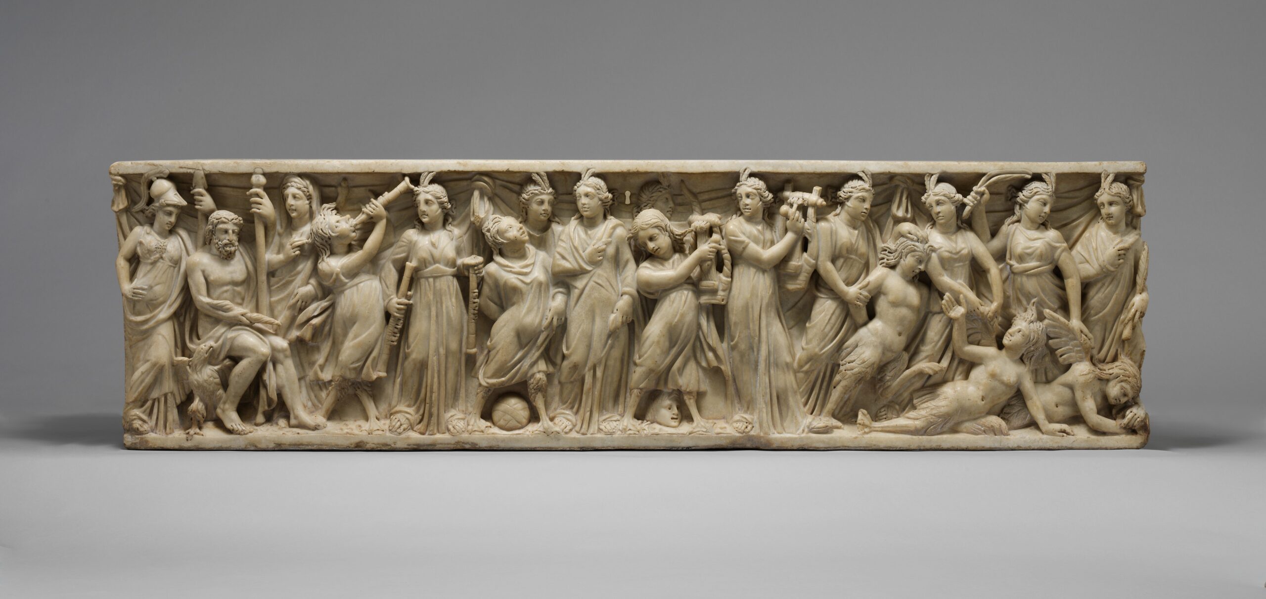 Long relief en marbre où s'alignent une vingtaine de figures drapées, certaines tenant des instruments de musique.