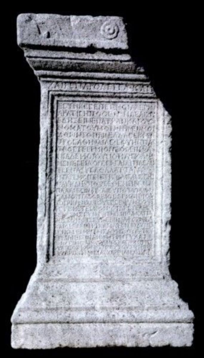 Autel funéraire en calcaire, photographié sur fond noir : un bloc rectangulaire à corniche moulurée, dont la face principale est entièrement couverte d'une inscription grecque gravée.  https://clasate.cimec.ro/Detaliu.asp?k=12DDD42681DD40648195B4E40888903D