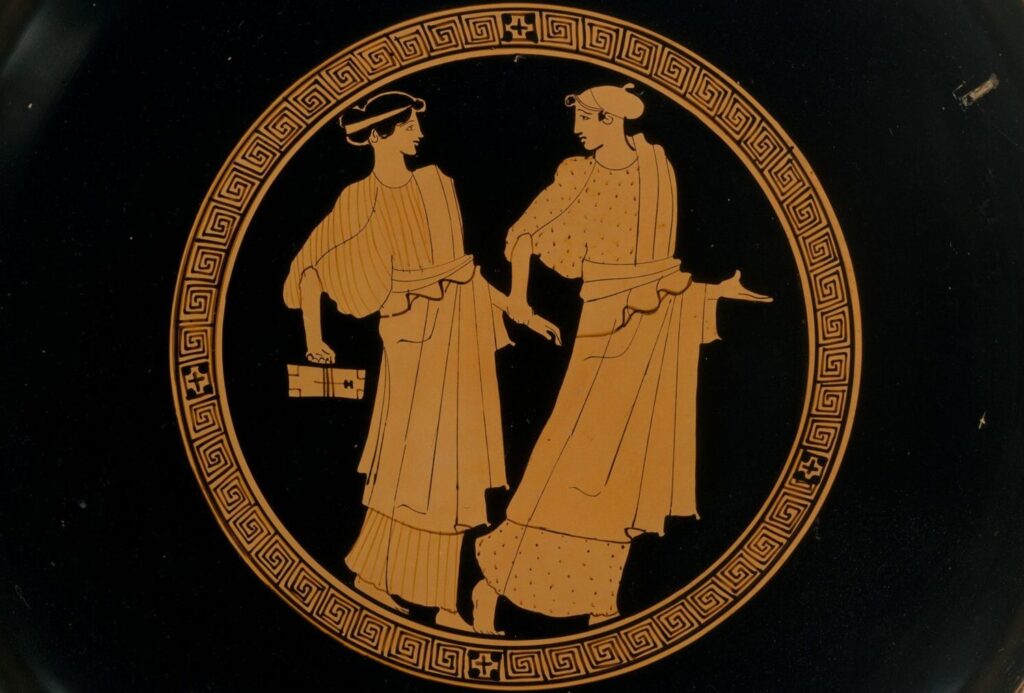 Médaillon intérieur d'une coupe grecque à figures rouges : deux jeunes filles debout, l'une tenant des tablettes et un stylet.
