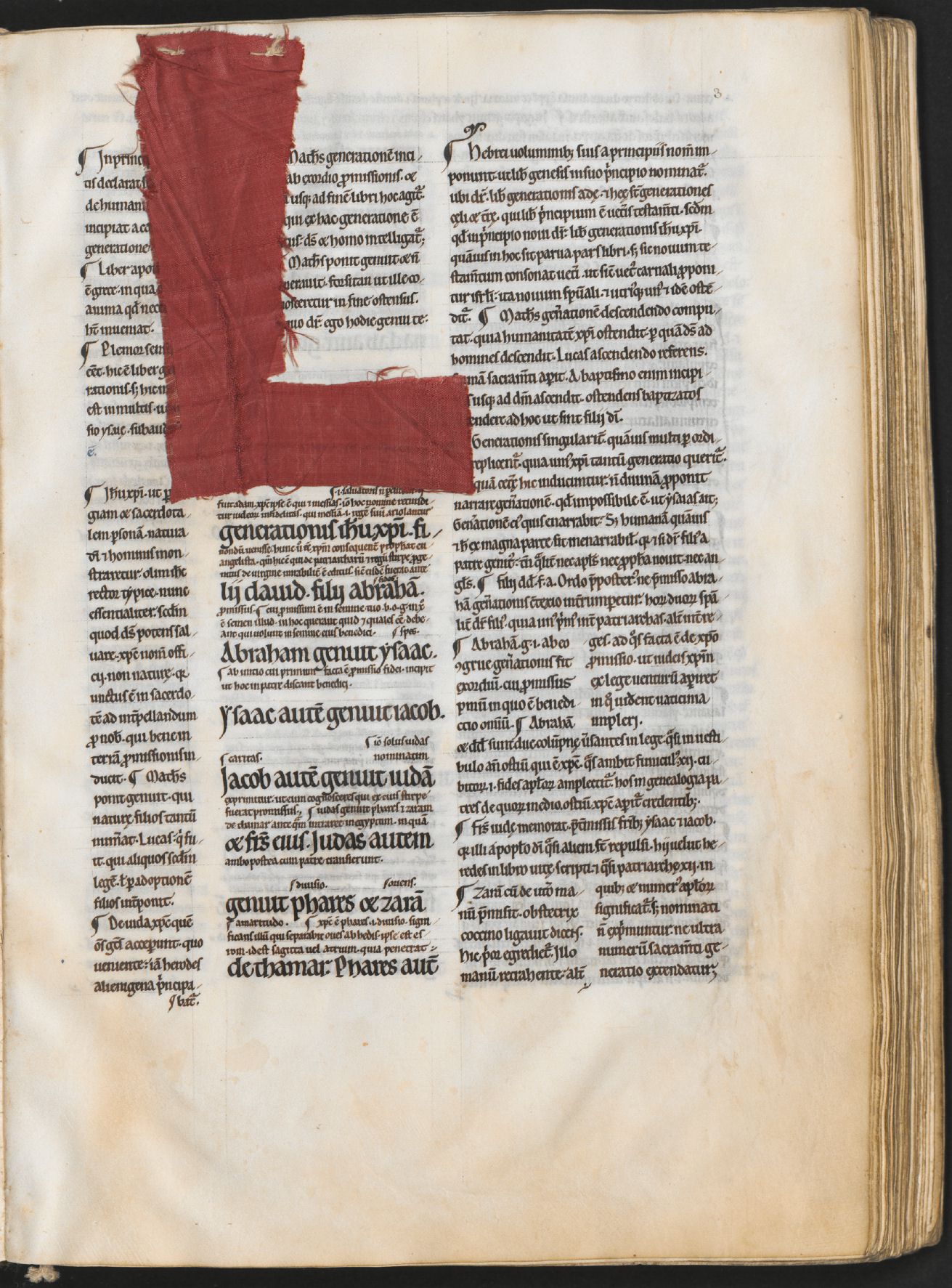 Page de manuscrit médiéval : une grande initiale ornée, partiellement recouverte d'un voile de tissu rouge.