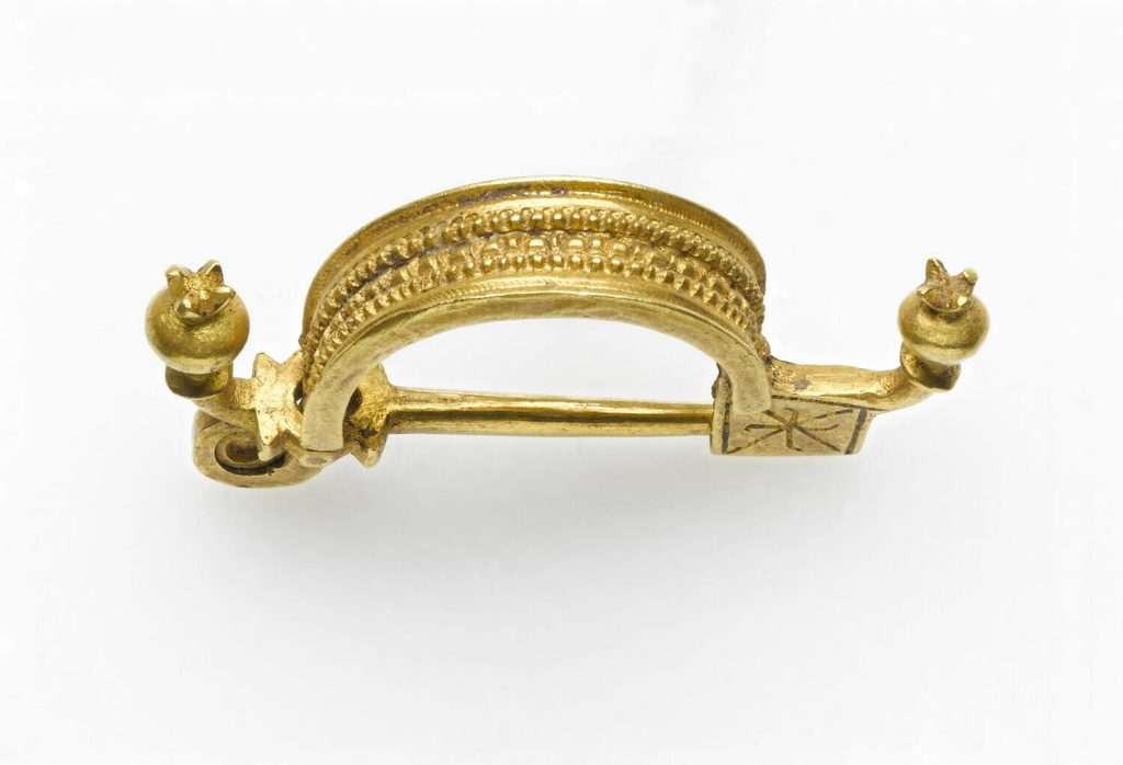 Petite fibule en or en forme de barque allongée, ornée de trois perles alignées sur son arc.