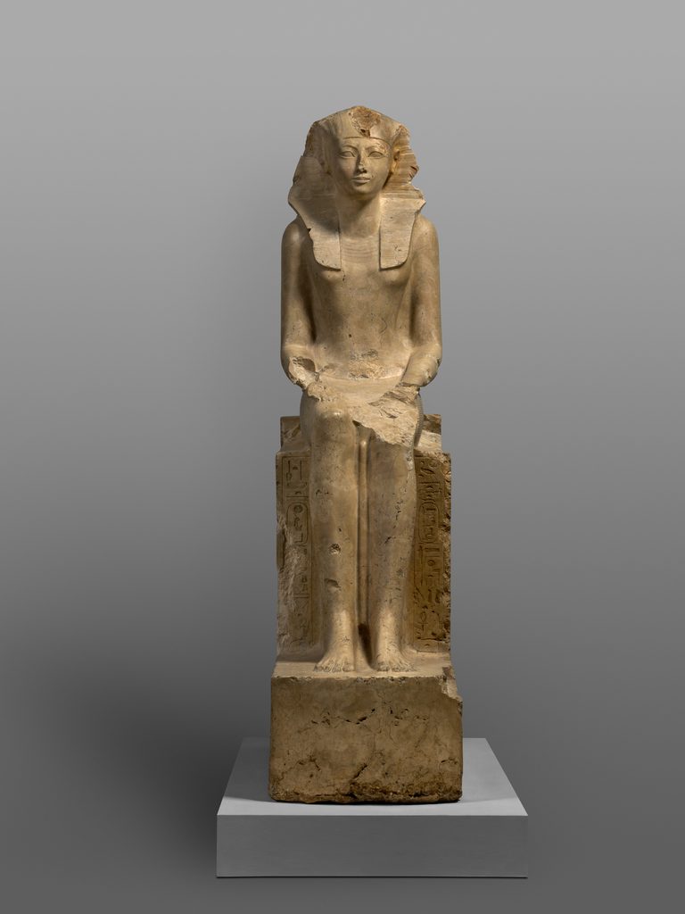 Statue en calcaire d'une figure coiffée du némès, vêtue d'un pagne, la poitrine légèrement marquée.