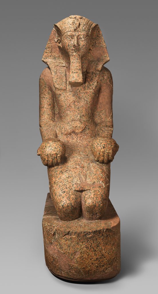 Statue colossale en granite, coiffée du némès rayé et portant une barbe postiche, le visage tourné vers l'avant.