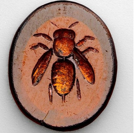 Petite pierre ovale rouge orangé, gravée en creux d'une figure.