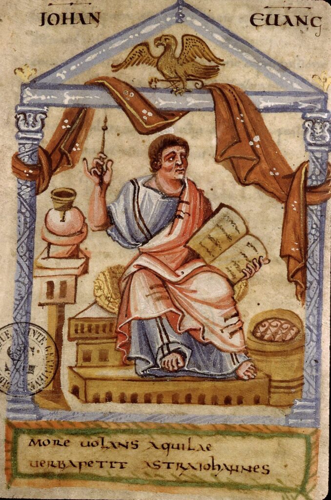 Enluminure de Saint Jean représenté assis dans une structure en forme de temple. Il tient un calame de sa main droite et un livre de sa main gauche.